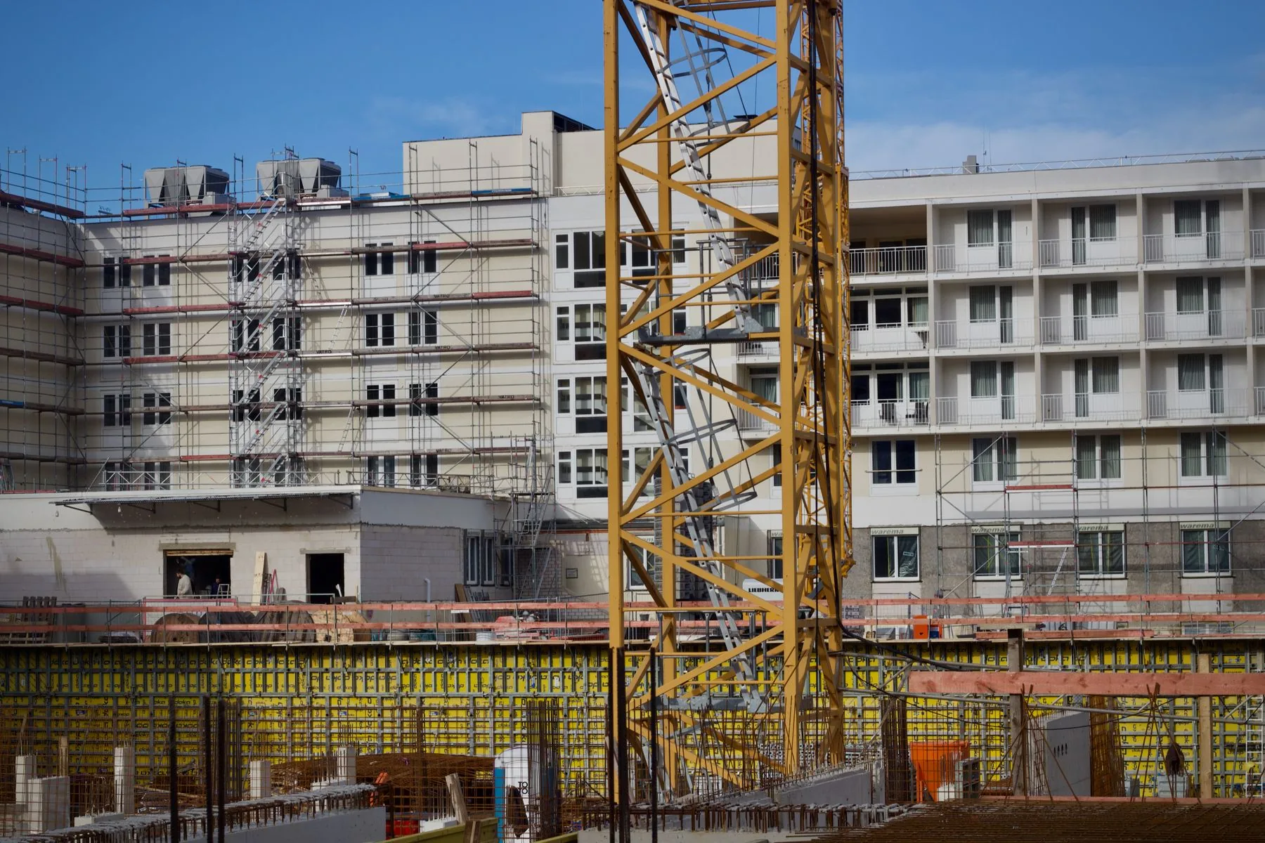 Building under construction beside a crane, illustrative photography
